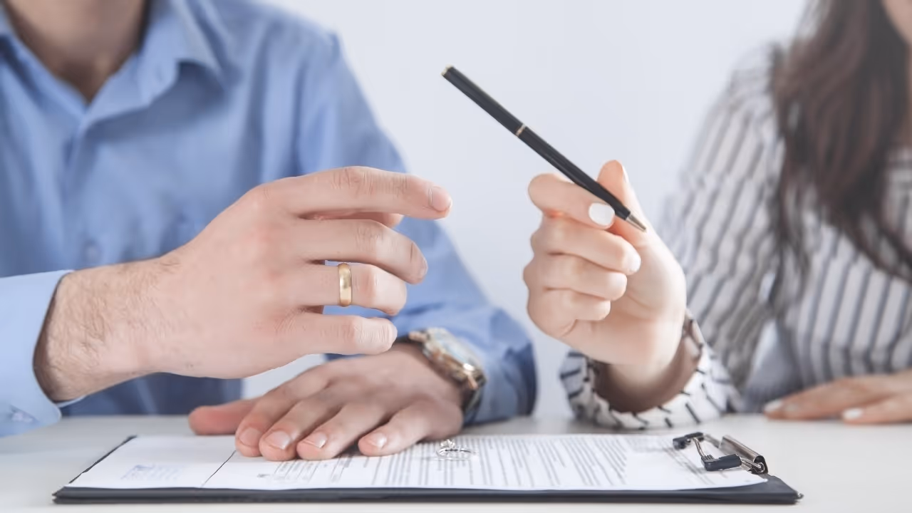 Two people discussing a contract on a clipboard, one holding a pen and the other hand resting on the document.